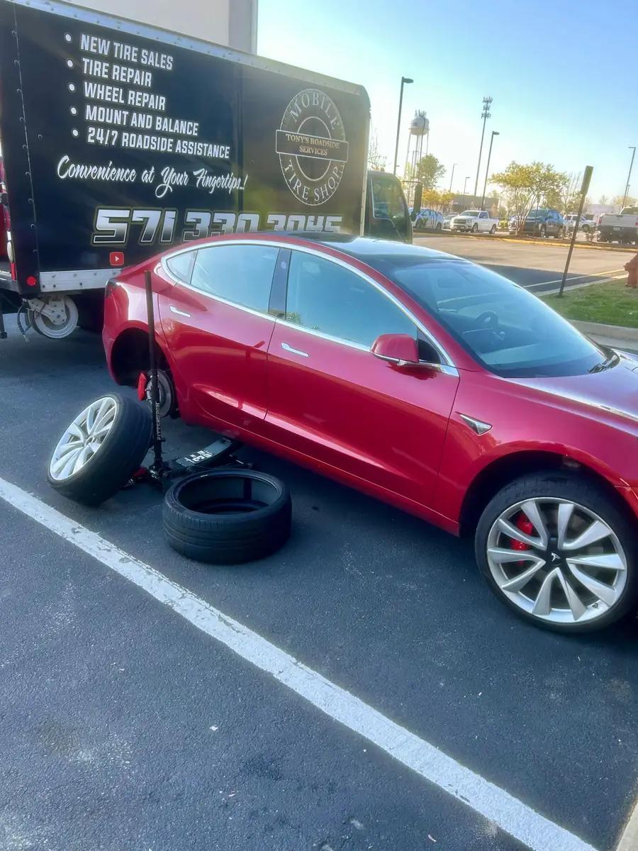 TRS mobile tire service working on a red Tesla in a parking lot