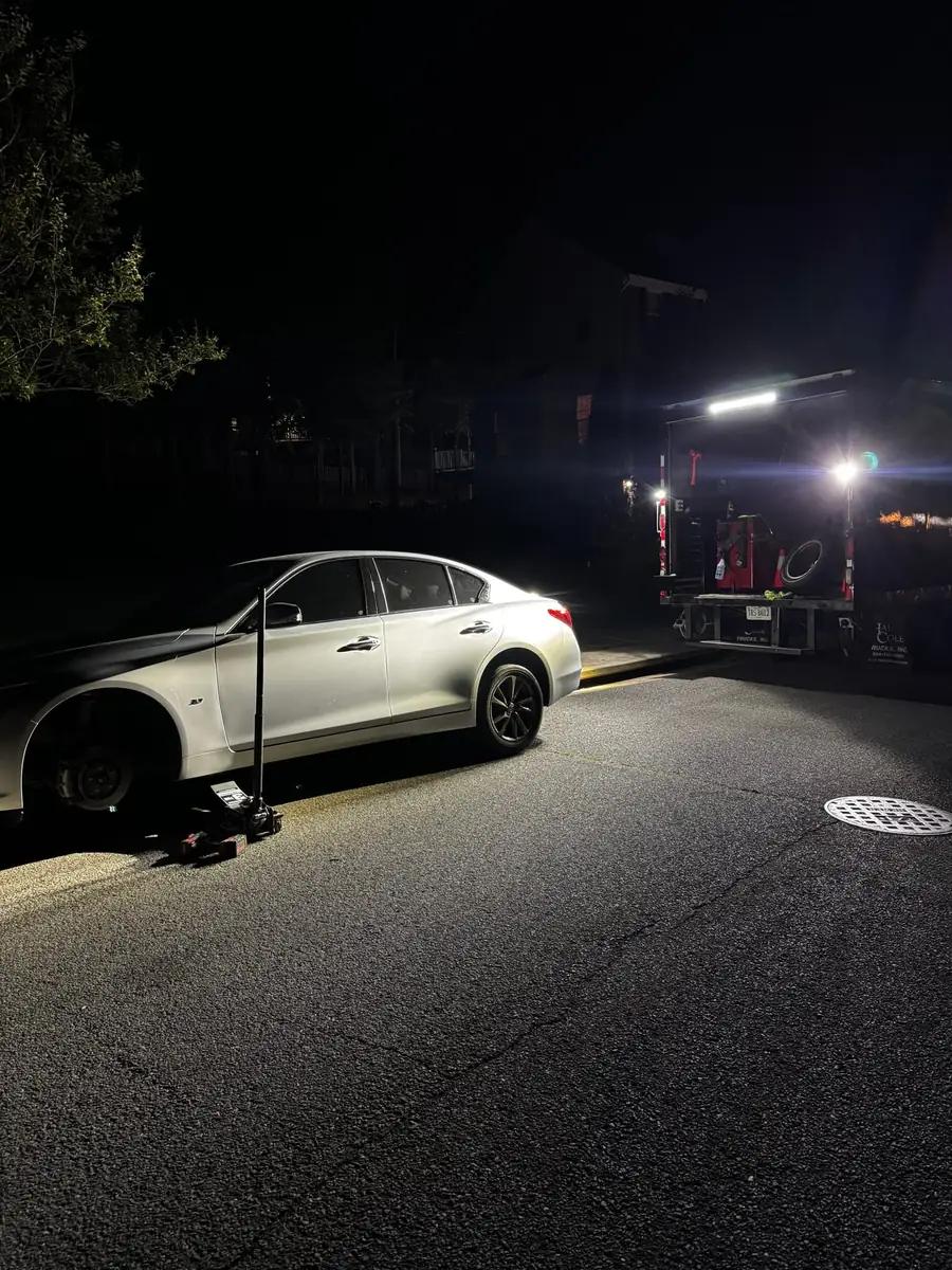TRS mobile tire service working on a sedan at night